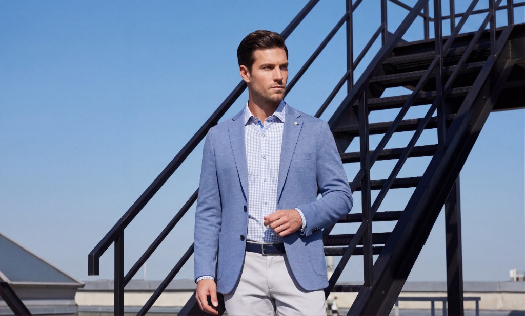 Man wearing a light blue sportcoat on a rooftop stairway